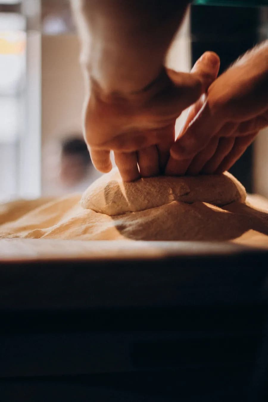 Des mains qui pétrissent une pâte sur un plan de travail fariné